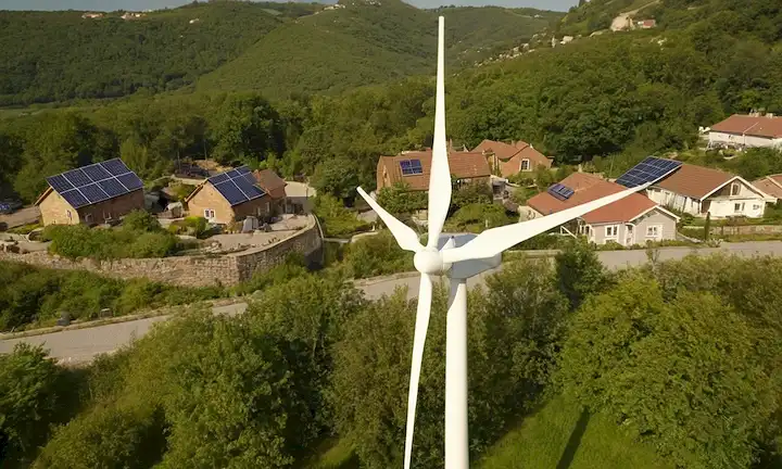 3-4 pequeñas a medianas turbinas eólicas instaladas en tejados, zonas residenciales y patios traseros, con un fondo soleado, posiblemente con vegetación, paneles solares u otros elementos ecológicos, transmitiendo un sentido de comunidad, sostenibilidad e integración en la vida cotidiana