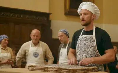 Hombre que demuestra la técnica tradicional de fabricación de azulejos ante un público de pares