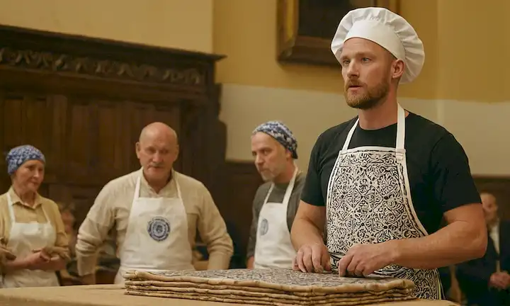 Hombre que demuestra la técnica tradicional de fabricación de azulejos ante un público de pares