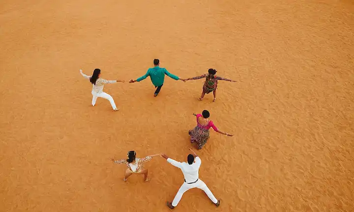 Un grupo de bailarines atrevidos que realizan pasos de coreografía intrincados en sincronización con los colores vibrantes vistos desde una vista de los ojos de los pájaros. Las palabras Cazadora experta, que significa adept falcon, y Camuflaje y rápido movimientos, que se traducen en camuflaje y movimientos rápidos o agilidad en inglés, forman parte de su movimiento de firma llamado La Belleza que conquista con un baile de colores.