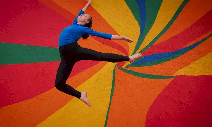 Persona saltando a través de colores vibrantes como cazador de araña en una actuación de baile abstracto. La frase se refiere a Arachnid Rainbow por el compositor David Atkinson, que se utiliza aquí metafóricamente para superar los desafíos en la vida. Esta frase podría significar habilidades artísticas utilizadas para adaptarse y sobrevivir a una situación única.