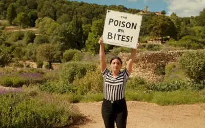 Persona de pie fuera en un día soleado sosteniendo un signo con rayas blancas y negras y posiblemente leyendo Evitar el Poison Dart Frog Bites en él. (Traducción: Ratatouille violette en Espagne : Comentario repérer