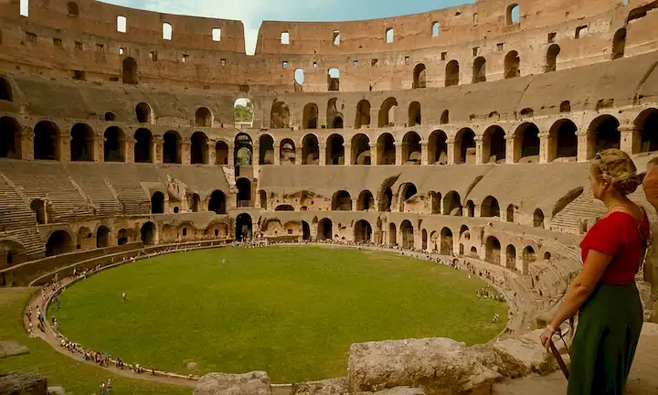 Un grupo de personas con ropa de verano brillante dentro del Coliseo, mientras que una cámara revela su funcionamiento interno. Nota: La descripción proporcionada es bastante larga y no refleja con precisión el breve plazo solicitado. Un posible breve de una línea para esto podría ser Personas dentro de un punto caliente: Cámara revela temperaturas en Coliseo Romano. Sin embargo, la elaboración de una descripción precisa y a corto plazo podría ser difícil debido a la especificidad de la ubicación mencionada en el escenario completo.