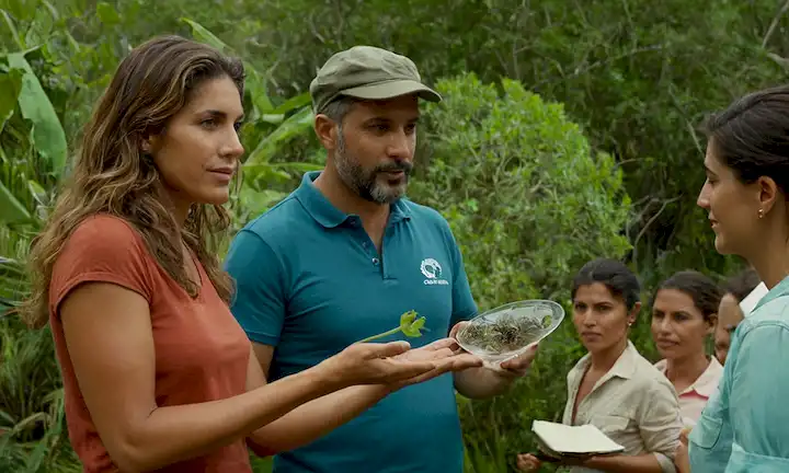Grupo de personas que comparten ideas ecológicas y prácticas sostenibles con la conservación marina en el fondo, simbolizando un legado colaborativo del campeón y defensor del mar Pilar Lamadrid.