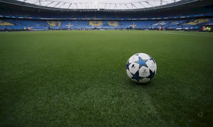 Representación artística de un campo de fútbol, césped verde vibrante, césped artificial, cleats, y guardias de shin, con símbolos sutiles de la Unión Europea o banderas subtly integrado en el diseño