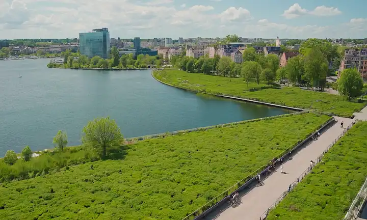 Paisaje urbano cubierto de vegetación, edificios sostenibles, transporte público, ciclistas, parques, lagos, cielo con sol o nubes, colores vibrantes, contaminación mínima, luz natural, techos verdes, renovación urbana