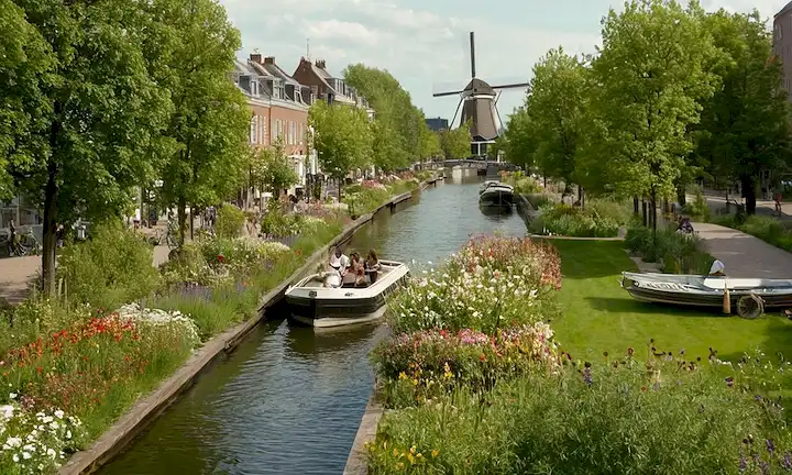 Tejados verdes, botes de canales, molinos de viento, bicicletas, bancos de parques, flores, vías acuáticas, arquitectura se mezcla con la naturaleza, paisaje urbano sostenible, diseño moderno, armonía entre humanos y medio ambiente, aire limpio, luz natural, bosque urbano, espacios verdes, gente disfrutando al aire libre