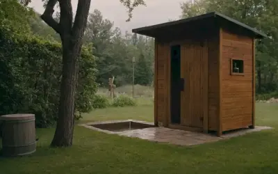 Una persona mirando un pequeño pozo de agua junto a una ducha al aire libre o fuera de casa