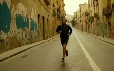 Persona corriendo en una calle urbana en medio del graffiti mientras advierte sobre una especie invasiva que amenaza con extenderse por España y más allá. (Referencing the article title Mad Cowards in Barcelona: The Invasive Species that could Spread Across Spain