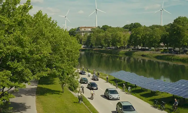 Paisaje urbano verde con paneles solares en tejados, turbinas eólicas generando electricidad, vehículos eléctricos y bicicletas estacionadas por árboles, personas caminando o ciclándose a lo largo de ríos y calles limpios, espacios públicos llenos de vegetación, conceptos de planificación urbana sostenible