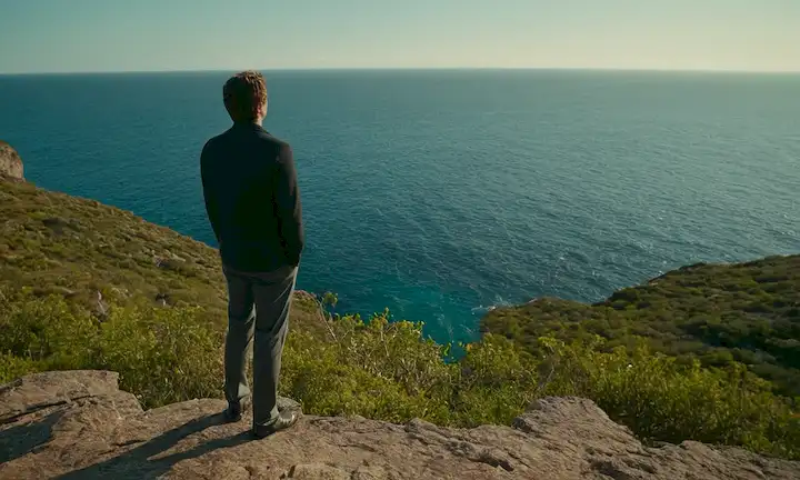Persona frente al horizonte observando un cuerpo transparente de agua, capturada con datos científicos y posibles precauciones de seguridad contra el ataque de Medusa.