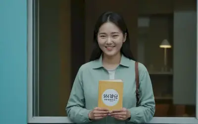 Las manos que sostienen un pequeño libro con el título coreano Mi Corea (묘) mostrado delante de ellos