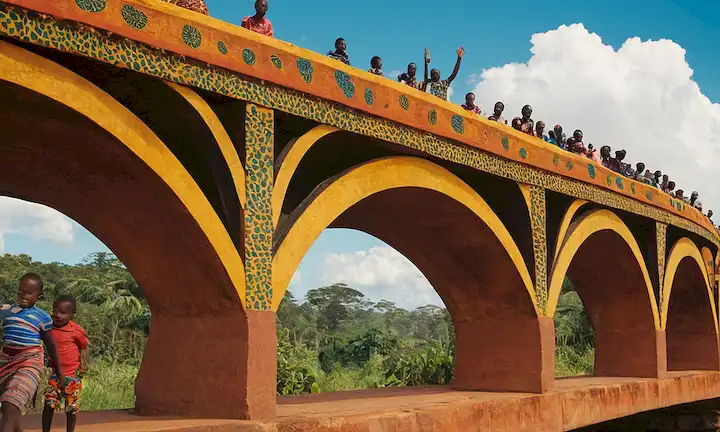 Un puente colorido y estilizado con las formas de la cultura africana en cada panel, representando Samis Cultural Journey: A Travel Through Ugandan Culture for Children ilustrado libro.