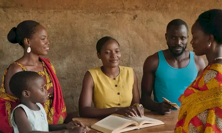 Título con nombres de autores y portada de libros con ilustración de personas dedicadas a la cultura ugandesa. Puede incorporar temas de amistad e intercambio cultural.