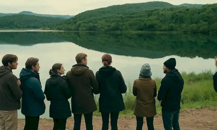 Un grupo de ecoactivistas de pie alrededor de un lago con preocupaciones ambientales planteadas, contra la minería y el desarrollo urbano.