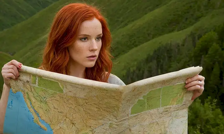 Mujer ondulada, con pelo rojo brillante y características pintadas usando un mapa para mostrar la ruta que atraviesa durante un viaje por montañas y valles. La cita de una EDUCACIÓN ES EL arma más poderosa que puedes usar para cambiar el mundo aparece debajo de su boceto en letra de caligrafía estilizada en su estilo artístico, con una técnica de medios de mezcla de cuchillo de paleta aplicada al papel.