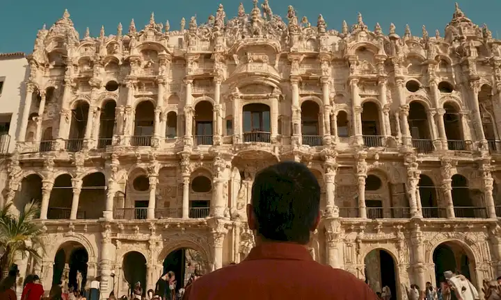 Aficionados a la arquitectura admirando la belleza de un edificio meticuloso elaborado como parte de un contexto cultural más grande. La frase está escrita en español y traducido al inglés como Ignacio Vicens: Arte