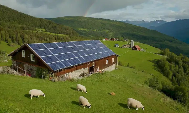 Campos verdes con pastoreo de ovejas, paneles solares en las laderas, turbinas eólicas girando, una planta de producción de color arco iris, y una pequeña granja de madera en medio de bosques y montañas exuberantes en el campo de Noruega