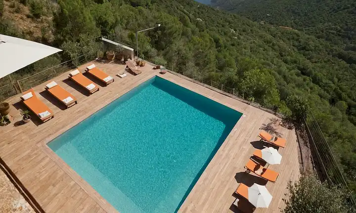 El objetivo realista de Sipping the Climate Away: Piscinas como alojamiento ecológico en Cataluña. Con un mapa de la región, y gotas de agua que representan un impacto ambiental potencial.