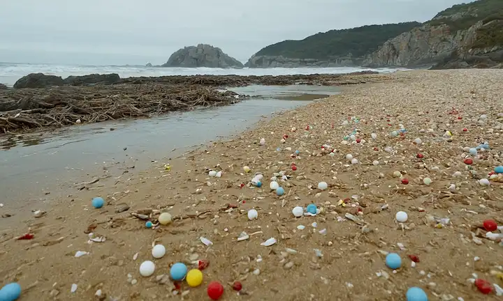 Lecciones aprendidas de bolas de plástico baratas: Playas en Galicia y Asturias todavía afectados. Una escena de playa con agua contaminada o escombros encendidos.