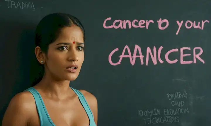 Persona de pie frente a un mensaje en una pared mientras se ve conmocionada, discutiendo la importancia de las campañas de educación e información sobre el cáncer. La campaña está dirigida por la actriz Poonam Pandey con el hashtag #FingertoyourCancer. Esta es una escena de una película que podría ser parte de esta historia.