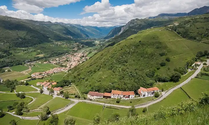 Vista aérea panorámica desde arriba para representar el pintoresco paisaje rodeado de exuberante vegetación y paisaje montañoso de la antigua ciudad de Bulnes en la región de Asturias, España. La leyenda hace hincapié en las prácticas turísticas sostenibles para preservar esta belleza natural. Para proporcionar más contexto sobre el nombre Bulnes un Destino Ideal, su origen podría ser extraído de palabras como:1) Un que significa uno2) Destino Ideal, lo que significa Destino Ideal, insinuando hacia un lugar perfecto para el turismo.3) Bulnes es un nombre de ciudad. Así que, si lo derriba en pasos, el nombre podría ser leído tal vez como Bulnes - Un Destino Ideal para el Turismo Sostenible. El nombre refleja un lugar ideal para promover el ecoturismo y las prácticas sostenibles. Ahora para explicar por qué este título específico podría ser apto: Bulnas en sí mismo, encaramado sobre una lofty colina, ejemplifica el pintoresco esplendor mientras que también es un símbolo de las regiones modelo turístico de bajo impacto resueltamente. Como lo hace..La ciudad está libre de coches, reflejando así el compromiso de reducir la huella de carbono y promover alternativas de viaje más ecológicas (como caminatas o bicicletas). También sirve de prueba para una sólida tradición agrícola que emplea métodos agrícolas tradicionales como el terrazo, lo que ayuda a conservar el agua. Esto se ajusta además a los principios del turismo sostenible haciendo hincapié en el patrimonio y la conservación del entorno natural. Esta ciudad, su encanto y sus prácticas ecológicas han llamado la atención entre los influencers y entusiastas del viaje en el pasado, lo que lo convierte en una de las principales atracciones para los turistas que buscan una escapada verde inmersiva mientras aprecian la cultura, las tradiciones y los paisajes locales. La frase un Destino Ideal para el Turismo Sostenible (un Destino Ideal para el Turismo Sostenible) encapsula perfectamente estos ideales, ambos reflejando el carácter de las ciudades a través de visuales pintorescas y sus ethos ecológicamente conscientes en términos de prácticas turísticas. El título es sugestivo de que este lugar no sólo ofrece una experiencia atractiva, sino que también garantiza un equilibrio entre disfrutarlo y preservarlo. Por lo tanto, Bulnes un Destino Ideal se puede interpretar como una invitación para explorar y apreciar la rica historia, cultura y paisaje, apoyando al mismo tiempo el crecimiento sostenible en este destino de viaje único.