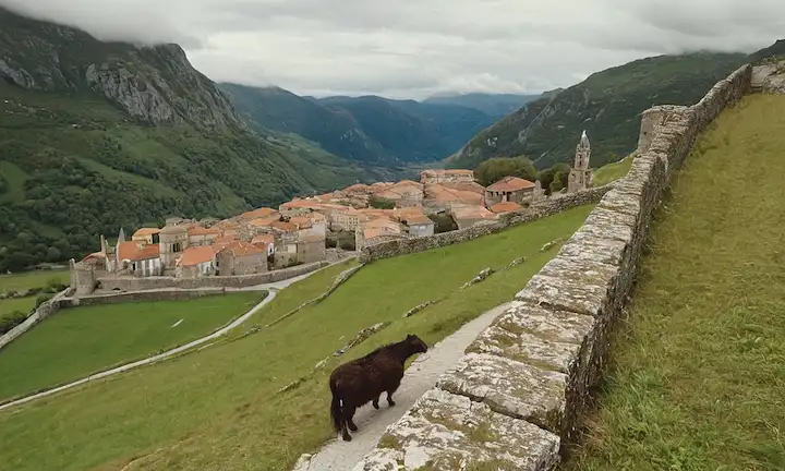 El viajero se entremezcla a través de la antigua piedra con una vista panorámica en el fondo. (Traducción: Paseo por las atracciones de Búlnes, Asturias: El último pueblo sin coches en un paraíso de montaña.)