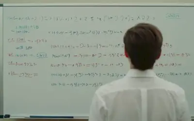 Una persona de pie delante de una pizarra con ecuaciones matemáticas escritas en ella.