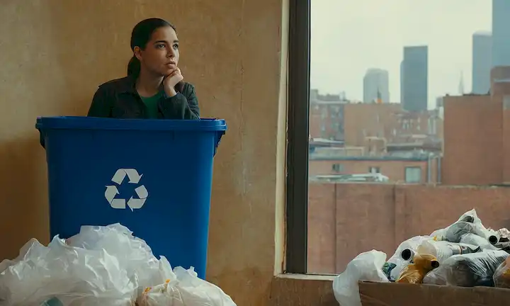 Una persona que sostiene un contenedor de reciclaje, rodeado de bolsas de basura y materiales reciclables, mirando preocupado por una burbuja de pensamiento, un montón de residuos no reciclables en el fondo, un símbolo de reciclaje en la pared, un esbozo débil de la Tierra desde detrás de la persona, y una pista de un paisaje urbano fuera de la ventana