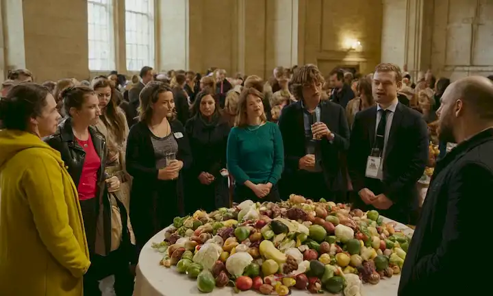 Las personas se reunieron en un evento discutiendo su experiencia compartida con los desechos y la distribución de alimentos, destacando los impactos sociales positivos de su iniciativa.
