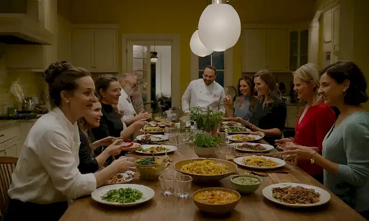Un equipo de individuos empoderados unidos en la cocina sobre una gran mesa compartida, compartiendo su visión para reconstruir el mundo culinario después de perder liderazgo. Con platos de colores brillantes y utensilios que los rodean, todos comparten emoción y optimismo por lo que el futuro sostiene.