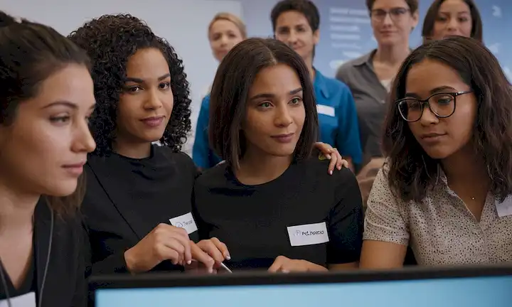 A diverse group of women in technical roles working together to overcome STEM gender barriers with the support of the community through Reinventa- Tech 2.0s Conclusiones event, with a computer graphics background and imagery related to technology.