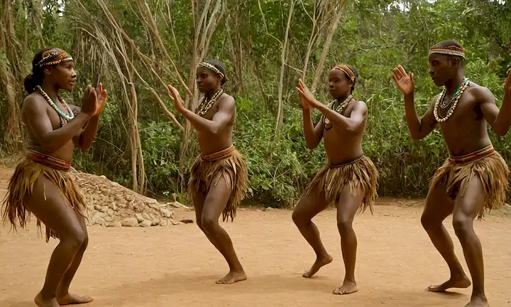 Un grupo de jóvenes que realizan danzas ambientales tradicionales se mueve mientras explican la importancia y los beneficios de la ecodance para su cultura y planeta. Traducción en inglés proporcionada: Educación Ambiental: Una herramienta clave para los Baboons: La danza del aire de los Cuernos de Bongo Tallest.