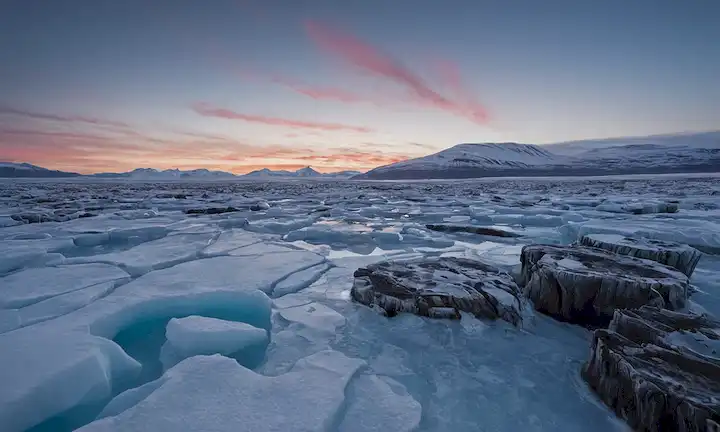 hojas de hielo brillando bajo el crevabo ártico, terreno montañoso robusto, burbujas de metano escapando crevasses helados, tórax de árboles antiguos sumergidos en tundra congelada, nubes espeluznantes de dióxido de carbono que suben del paisaje permafrost descongelado