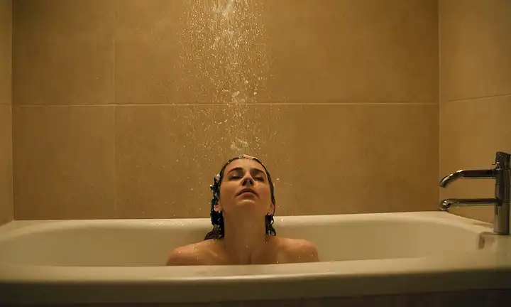 Persona salpicando en una bañera, acompañada de gotas de agua cayendo de una puerta de baño abierta. La frase implica que al mantener adecuadamente la higiene adecuada durante el baño (como reemplazar la cadena y cerrar la cubierta de drenaje), se pueden evitar experiencias desagradables.