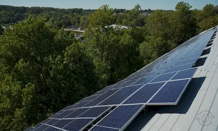 paneles solares instalados en una azotea con un fondo de cielo azul, con algunas sombras echadas de edificios o árboles cercanos, destacando los desafíos de durabilidad y mantenimiento de techos solares, con una variedad de ángulos y orientaciones de panel, con alambres y conexiones visibles para enfatizar la importancia de upkeepep