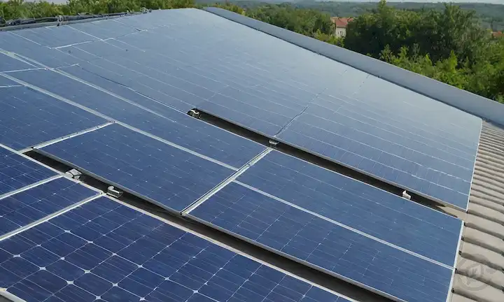 Tejas fotovoltaicas en una azotea, soleado día, cielo azul, entorno verde, fachada de construcción, arquitectura moderna, integración de energía solar, tecnología innovadora, generación de energía limpia, futuro sostenible, paneles interconectados y rayos de luz solar
