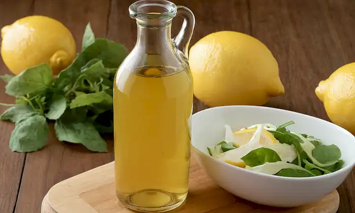 Vino de limón y blanco como ingredientes en una vinagreta casera, con alternativas ecológicas discutidas. (En términos simples, esto podría interpretarse como jugo de limón mezclado con vinagre de vino blanco para aderezos de ensalada más saludables.)
