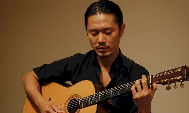 Yoichiro Yamada, apasionadamente abrazando su pasión por el flamenco mientras toca la guitarra y el canto. Esta breve descripción implica un atractivo espectáculo musical de un talentoso músico flamenco.